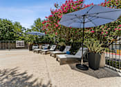 Thumbnail 16 of 20 - Pool deck with lounge chairs and umbrellas at Knoll Crest Apartments, Texas, 78240