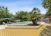 Thumbnail 12 of 20 - Pool deck with palm trees and lounge seating at Knoll Crest Apartments, San Antonio, 78240
