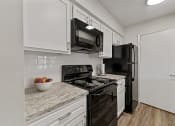 Thumbnail 39 of 47 - a kitchen with white cabinets and black appliances at The Hudson, Texas