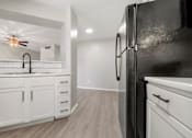Thumbnail 21 of 38 - a renovated kitchen with white cabinets and a black refrigerator at Polo Clubs Apartments, Texas, 78729