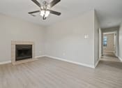 Thumbnail 23 of 38 - an empty living room with a fireplace and a ceiling fan at Polo Clubs Apartments, Austin, TX