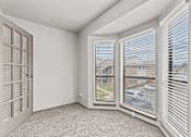 Thumbnail 18 of 43 - A room with a carpeted floor, a window with blinds, and a door with a window.at Rock 35, Round Rock