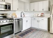 Thumbnail 23 of 79 - a kitchen with white cabinets and steel appliances at Sunset Heights, San Antonio