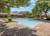 Thumbnail 5 of 29 - A small pool surrounded by a gravel area and trees.