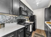 Thumbnail 32 of 58 - a kitchen with black cabinets and white countertops at Vesper, Dallas, 75254