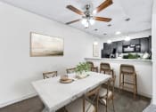 Thumbnail 43 of 58 - a dining area with a table and chairs, a ceiling fan and a kitchen in the background  at Vesper, Dallas, TX, 75254