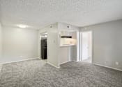 Thumbnail 35 of 63 - the spacious living room and kitchen of an apartment with white walls and carpet at The Keller, San Antonio Texas  