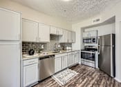 Thumbnail 4 of 26 - A kitchen with white cabinets and stainless steel appliances.