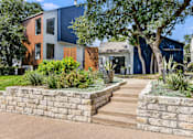 Thumbnail 2 of 15 - a stone retaining wall in front of a house with stairs at Peaks at Northwest Hills Apartments, Austin, TX 78731