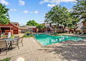 Thumbnail 7 of 32 - A pool surrounded by chairs and trees in a sunny day.