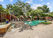 Thumbnail 3 of 32 - A pool surrounded by trees and a building in the background.