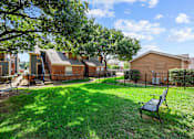 Thumbnail 11 of 32 - A backyard with a bench and a tree.