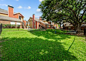 Thumbnail 12 of 32 - A backyard with a green lawn and a tree.