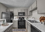 Thumbnail 26 of 32 - A kitchen with a black refrigerator and a black oven.