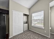 Thumbnail 17 of 32 - A room with a white door, a window with blinds, and a black refrigerator.