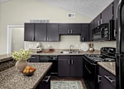 Thumbnail 18 of 32 - A kitchen with black appliances and cabinets.