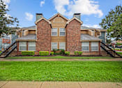 Thumbnail 15 of 32 - A brick house with a green lawn in front.