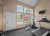 Thumbnail 14 of 32 - A gym room with a treadmill, exercise bike, and other equipment.