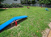 Thumbnail 49 of 53 - A blue seesaw in a grassy playground area.