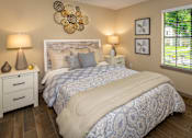Thumbnail 5 of 10 - A bedroom with a large bed and a white nightstand with two lamps.