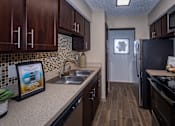 Thumbnail 4 of 10 - A kitchen with a fridge, stove, and sink.