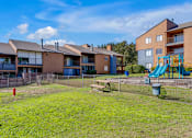 Thumbnail 14 of 28 - A playground with a slide and a fire hydrant is in front of apartment buildings.
