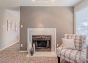 Thumbnail 2 of 27 - A living room with a fireplace and a chair.