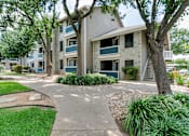 Thumbnail 8 of 38 - an apartment building with a walkway and trees in front of it