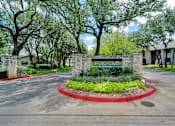 Thumbnail 1 of 38 - a sign for a parking lot with plants in front of a building