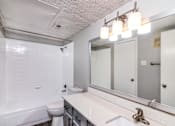 Thumbnail 9 of 27 - A white bathroom with a toilet, sink, and mirror.