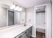 Thumbnail 7 of 27 - A bathroom with a white counter top and a mirror above it.