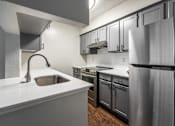 Thumbnail 2 of 27 - A modern kitchen with a stainless steel refrigerator and a white countertop.