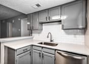 Thumbnail 11 of 27 - A kitchen with a sink and a dishwasher.