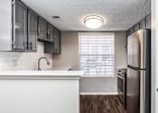 Thumbnail 4 of 27 - A kitchen with a white counter top and a stainless steel refrigerator.