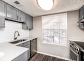 Thumbnail 3 of 27 - A kitchen with a white counter top and a stainless steel sink.