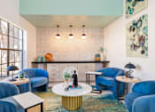 Thumbnail 25 of 27 - A living room with blue chairs and a white coffee table.