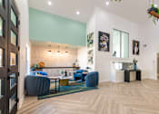 Thumbnail 26 of 27 - A living room with a blue couch and a wooden floor.