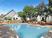Thumbnail 23 of 27 - A swimming pool surrounded by chairs and trees.