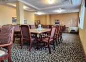 Thumbnail 8 of 12 - Community room with a table surrounded by chairs.