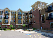 Thumbnail 4 of 12 - Apartment complex with a parking lot in front.