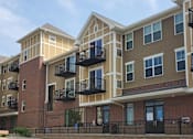 Thumbnail 5 of 12 - Apartment complex with balconies and a clear sky.