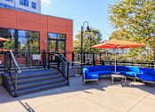 Thumbnail 28 of 29 - A blue couch is on a patio with a red umbrella.