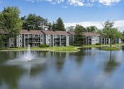 Thumbnail 34 of 36 - a fountain in the middle of a lake with an apartment building in the background