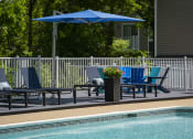 Thumbnail 7 of 27 - a swimming pool with blue chairs and a blue umbrella