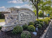Thumbnail 3 of 19 - Clinton Place Apartment Homes sign with a stone pillar and bushes.