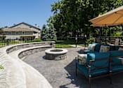 Thumbnail 22 of 23 - A patio with a fire pit and a blue couch.