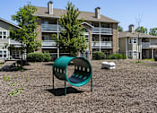 Thumbnail 20 of 23 - A green playground slide in front of apartment buildings.