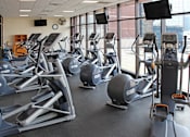 Thumbnail 9 of 13 - A gym with treadmills, elliptical machines, and other cardio equipment.