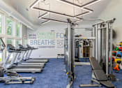 Thumbnail 13 of 20 - A gym with a row of treadmills and a row of exercise bikes.