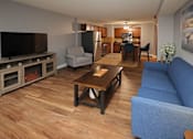 Thumbnail 4 of 13 - A living room with a blue couch and a wooden coffee table.